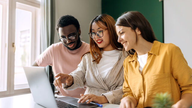 University students working on a project together using a tablet in a library.