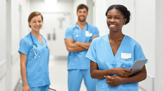 Smiling multi-ethnic medical professionals are standing in a corridor in a hospital.