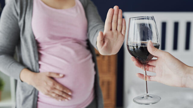 Pregnant woman refusing a glass of wine.